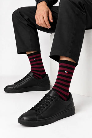 جوارب Tommy Hilfiger سوداء ونبيتي يرتديها رجل مع حذاء رياضي أسود.