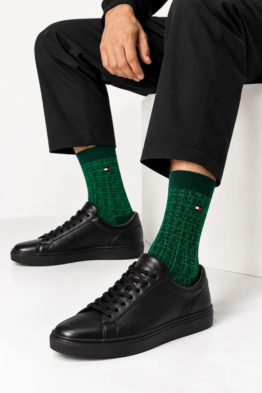رجل يرتدي جوارب Tommy Hilfiger خضراء بنقشة هندسية مع حذاء رياضي أسود.